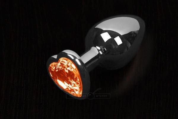 Большая анальная пробка Пикантные Штучки с оранжевым кристаллом в виде сердечка, серебристая, 8.5 см